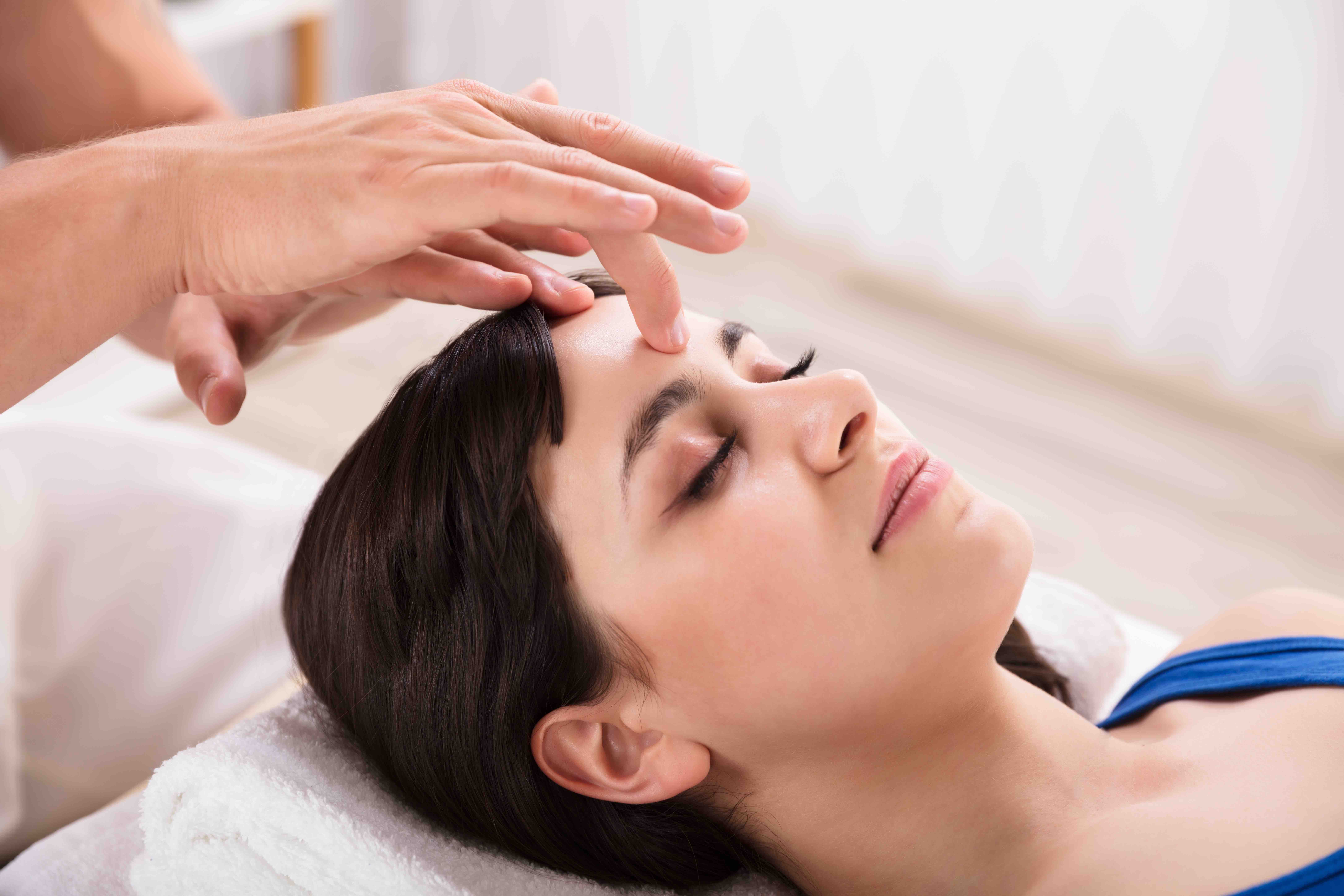 Close-up Of A Calm Young Woman Receiving Reiki Treatment In Spa
